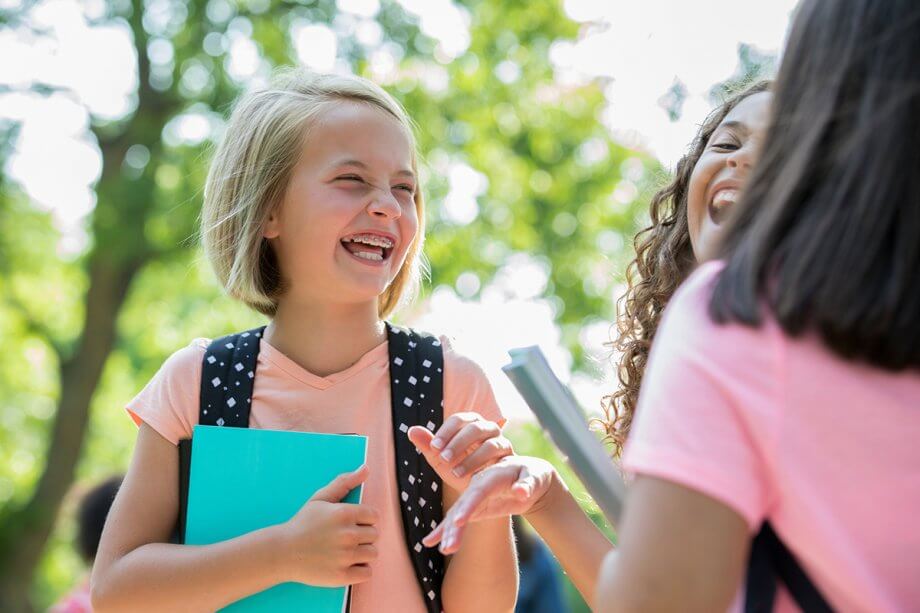 young girl with braces laughs with friends