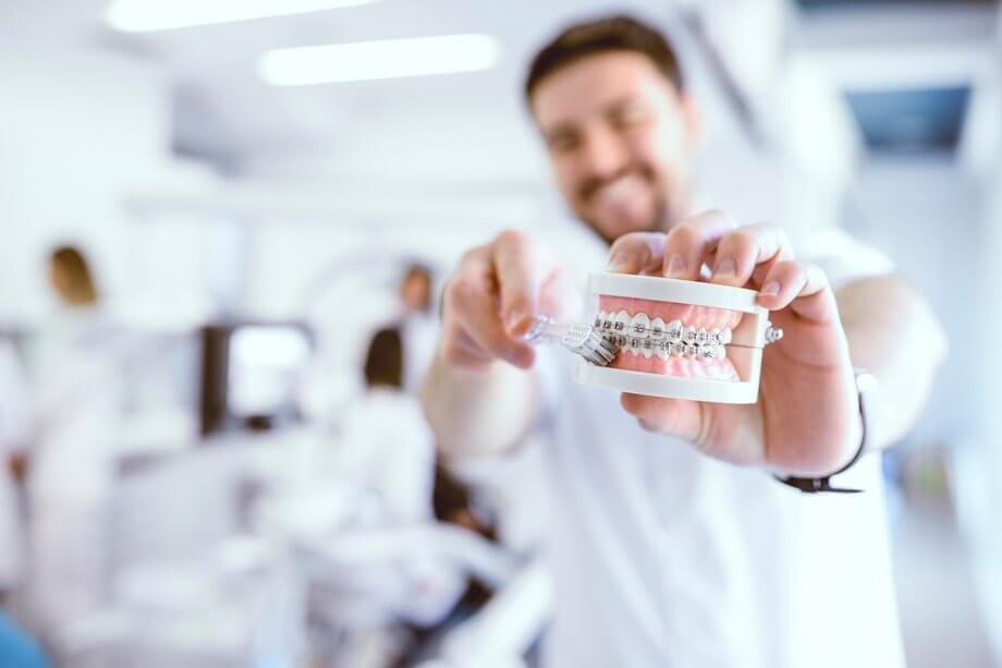 person brushing the teeth of a braced dental cast